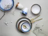 A flat lay of a stoneware dinnerware set including plates, bowls, and mugs, arranged with decorative elements like a dried branch and small white beads. Náhľad obrázku produktu