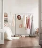 A bedroom scene with a clothing rack displaying various dresses and accessories. Produktbild-Vorschau