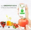 A hand holds a Greentest ECO 6 device measuring a tomato, with fruits and juice in the foreground. Produktbild-Vorschau
