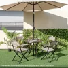 A patio set with a table and chairs under an umbrella, surrounded by artificial greenery and grass. Náhled obrázku produktu