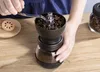 A person is using a manual coffee grinder to grind coffee beans. Náhľad obrázku produktu