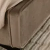 A close-up view of the upholstered side of a bed frame, showing the fabric texture and piping detail. A light-colored blanket is draped over the top. Produktbild-Vorschau