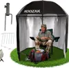 An elderly man sits in a fishing tent, preparing his fishing gear. The tent is set up on a patch of artificial grass, with fishing equipment scattered around. Anteprima dell’immagine prodotto