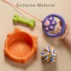 A collection of pet toys and a pet bowl arranged on a light beige surface, with a baby's hand holding one of the toys. Produktbild-Vorschau