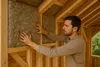 A man is installing insulation material into the wooden frame of a building. Anteprima dell’immagine prodotto