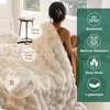 A woman is sitting on a bed, holding a white plush blanket. The image includes callouts and icons highlighting the blanket's features. Produktbild-Vorschau
