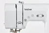 A close-up view of the top and side of a white Brother sewing machine. Podgląd zdjęcia produktu