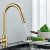 A gold kitchen faucet with water running into a sink, with vegetables on a cutting board in the background. Produktbild-Vorschau