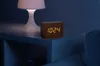 A wooden digital clock showing 10:24 is placed on a white nightstand next to a lamp. Anteprima dell’immagine prodotto