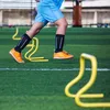 A person is training on a green field with yellow hurdles. Náhled obrázku produktu