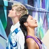 A man and a woman with earbuds in, leaning against a colorful graffiti-covered wall. Produktbild-Vorschau