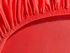 A close-up view of a red fitted sheet with elastic gathering. Produktbild-Vorschau