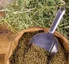 A close-up view of horse feed pellets in a brown paper bag, with a metal scoop partially submerged in the feed. A pile of hay is visible in the background. Produktbild-Vorschau