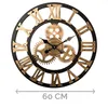A large, round wall clock with a black frame and gold Roman numerals and gears. Produktbild-Vorschau