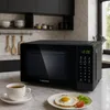 A black microwave oven is shown on a kitchen counter next to a cup of tea and a plate with a fried egg. Anteprima dell’immagine prodotto