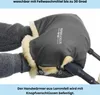 Hands wearing knitted gloves are inserted into a gray hand warmer lined with sheepskin, attached to a stroller handle. Produktbild-Vorschau