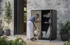 A woman is interacting with her dog next to an open outdoor storage cabinet. Produktbild-Vorschau