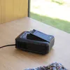 A black Bosch battery charger sits on a wooden surface near a window. Náhled obrázku produktu