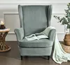 A gray wingback chair with a blanket and a book on it, next to a side table with a lamp and a basket with plants. Podgląd zdjęcia produktu