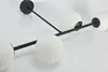 A close-up, angled view of a modern black ceiling light fixture with four white glass globe shades, set against a white background. Produktbild-Vorschau
