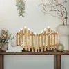A wooden fence decoration with LED lights and snowflakes, placed on a shelf with other Christmas decorations. Náhľad obrázku produktu