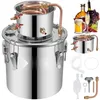 A stainless steel distiller with various accessories and beverages in the background. Náhľad obrázku produktu