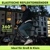 A man is riding a bicycle at night, wearing reflective bands on his arms and legs. Anteprima dell’immagine prodotto