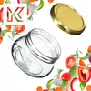 A glass jar and its lid are shown with various vegetables and herbs arranged around them. Voir les images du produit