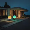 Two solar garden lights with colorful changing lights are placed on a walkway in front of a modern house at dusk. Produktbild-Vorschau