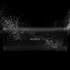 A black Sony Bluetooth speaker is shown against a black background with water droplets splashing around it. Voir les images du produit
