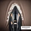 A close-up overhead view of a black and gold cordless steam iron on a brown textured fabric surface, with steam emanating from the iron. Produktbild-Vorschau