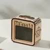 A small, wooden, cube-shaped object resembling a guitar amplifier, with a speaker grille, knobs, and a handle on top. It has a pentagram symbol on its side. Voir les images du produit