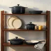 Cookware arranged on wooden shelves against a concrete wall. Produktbild-Vorschau