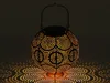 A decorative metal lantern casting intricate patterns of light on a dark surface. Produktbild-Vorschau
