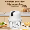A white electric kitchen chopper is shown on a countertop with a bowl of salad and some dumplings in the foreground. Jars of food are in the background. Produktbild-Vorschau
