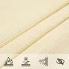 A close-up view of a cream-colored fabric, likely a sun sail, with four icons at the bottom representing water resistance, UV protection, wind resistance, and privacy. Náhled obrázku produktu