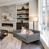 A dog is resting on a gray pet sofa in a living room with a fireplace and bookshelves. Voir les images du produit