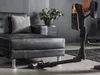 A person is holding a vacuum cleaner in a living room setting. Produktbild-Vorschau
