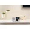 A white Blaupunkt portable radio sits on a white shelf next to decorative plants and glass jars. Náhled obrázku produktu