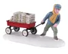 Miniaturfigur eines Jungen, der im Schnee einen roten Wagen zieht, der mit Zeitungen beladen ist. Náhled obrázku produktu