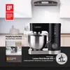 A black stand mixer is shown with a cookbook in the foreground, and a graphic award logo in the upper left corner. Podgląd zdjęcia produktu