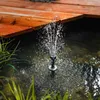 A solar-powered fountain is operating in a pond next to a wooden deck. Produktbild-Vorschau