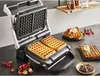 A waffle maker with freshly made waffles and toppings on a kitchen counter. Voir les images du produit