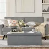 A living room scene with a gray sofa, a storage ottoman, and decorative items. Náhled obrázku produktu