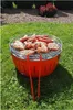 A charcoal grill filled with various meats and sausages, placed on a grassy lawn. Produktbild-Vorschau