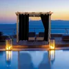 A pergola with black curtains next to a pool at sunset. Náhled obrázku produktu