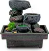 A tabletop water fountain with multiple tiers of stacked stones and bowls, with water flowing between them. It is set against a white background. Produktbild-Vorschau