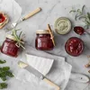 A festive arrangement of jam jars, cheese, and festive greenery on a marble surface. Produktbild-Vorschau