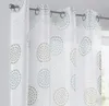 Close-up view of white curtains with a circular pattern in turquoise and beige, hanging from a metal curtain rod. Produktbild-Vorschau