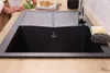 A black granite-look sink with a faucet and cleaning supplies on a wooden countertop. Produktbild-Vorschau